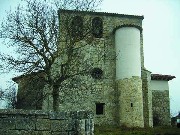 Imagen de la iglesia de San Román, en la que se aprecia la torre y el atrio exterior de piedra.